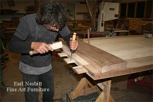Earl pegging tenons at one end of custom made dining table showing tenons